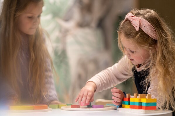 Two children playing with colorful wooden blocks on a table.