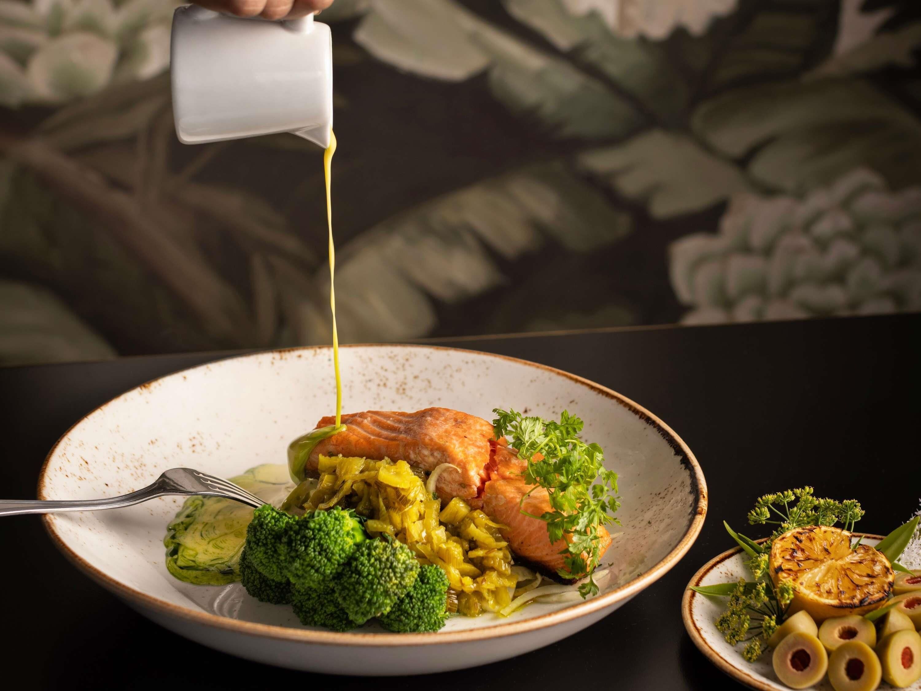 A plate of food with a fork, a bowl of olives, and a decorative plate with a lemon slice.