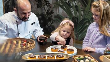 A dining table with various pastries and a chef.