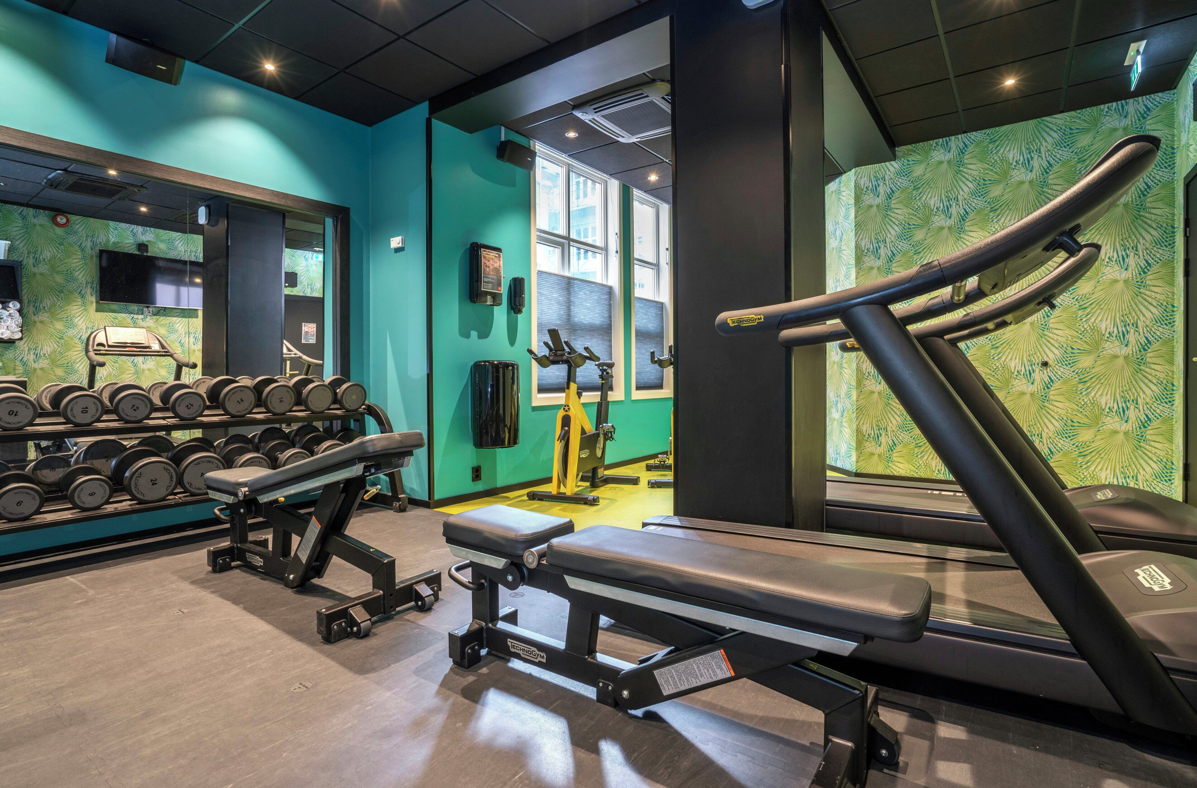 Un gimnasio con equipo de ejercicio, una banca y una cinta de correr.
