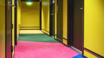 A hotel hallway with doors numbered 20 and 21, carpeted in pink and blue, and yellow walls.