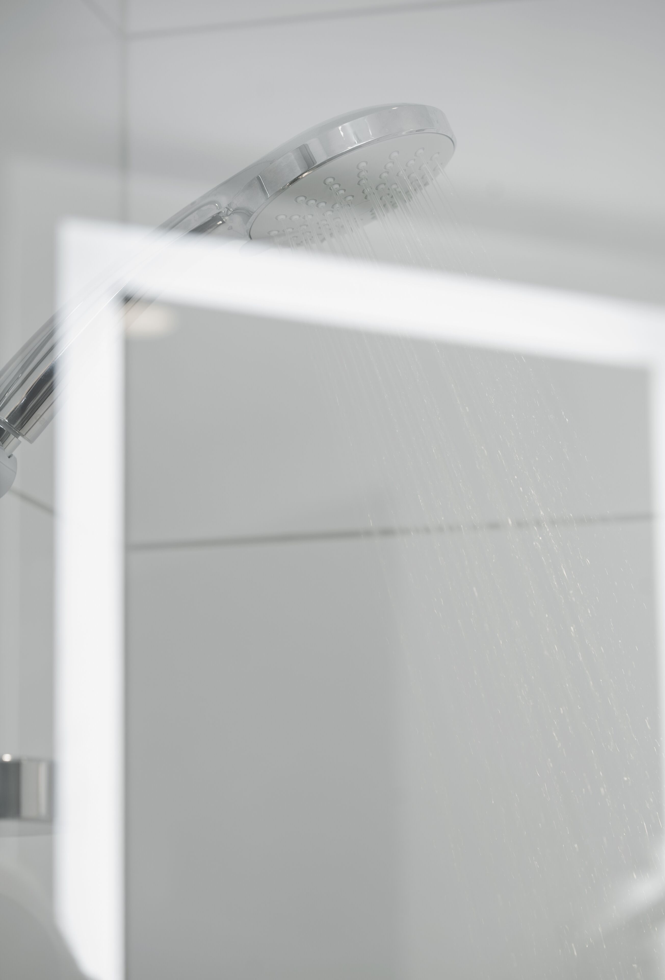 A shower with water flowing from a transparent showerhead.