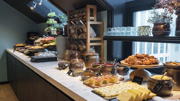 Un bufé con diversos alimentos, incluyendo queso, pasteles y salsas.