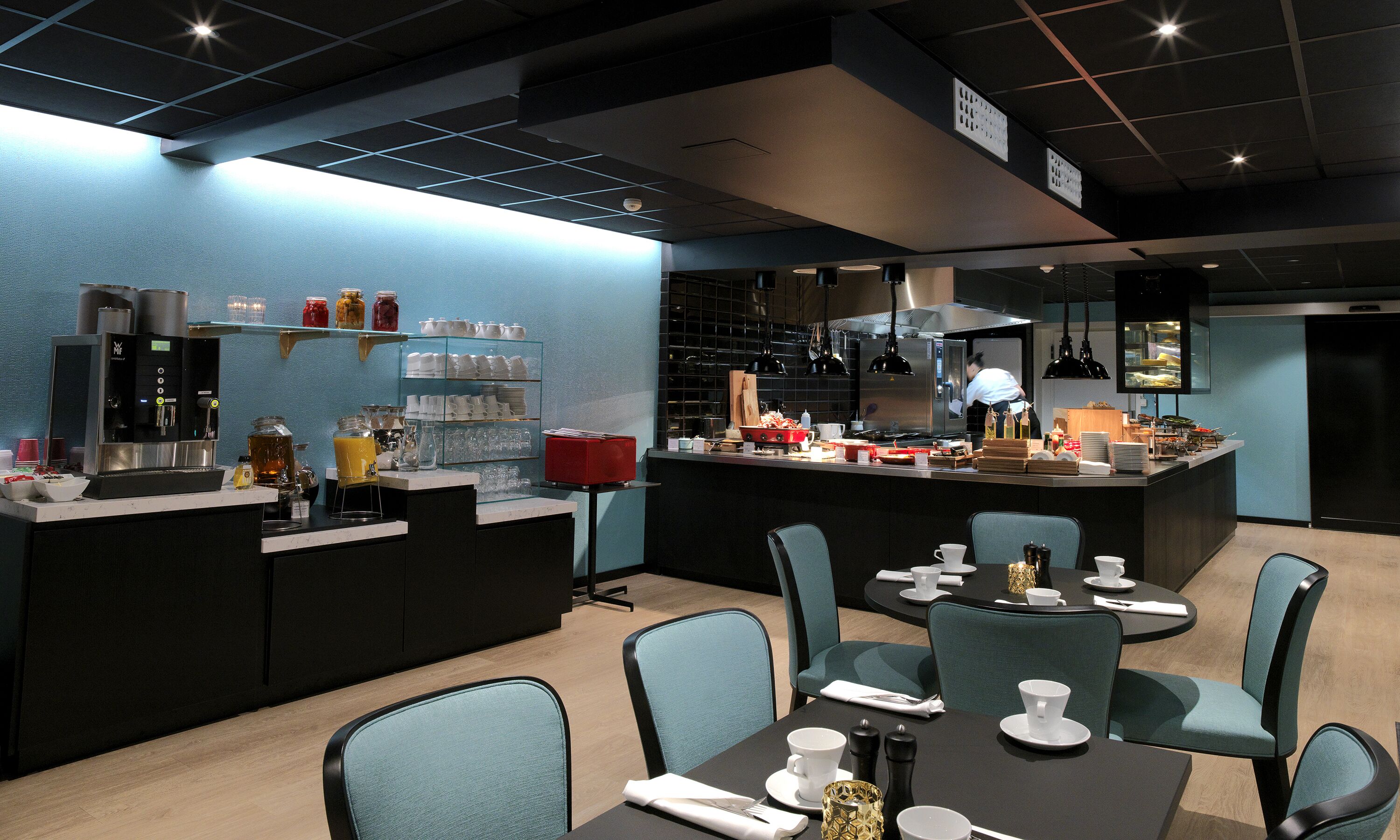 A modern cafe with a bar area, seating, and a kitchen in the background.