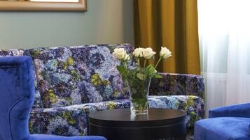 Una habitación con un sofá azul, una mesa redonda negra y un jarrón con flores blancas.