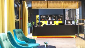 A reception area with a black counter, blue chairs, and a small table with a plant. - Thon Hotel Orion (Bergen)