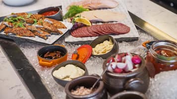 A charcuterie board with various meats, cheeses, and condiments on ice.