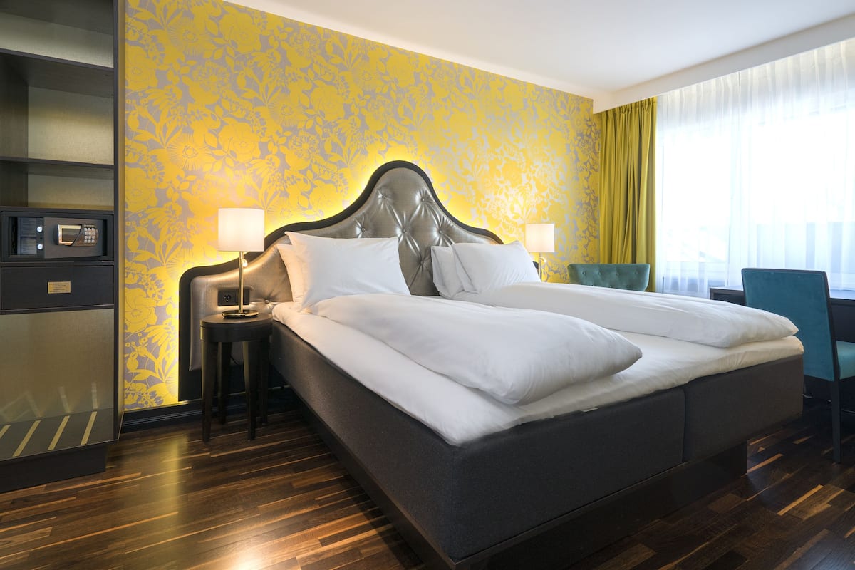 A hotel room with a large bed, bedside tables, a desk, and a chair.