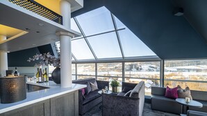 A modern interior with a bar area, seating, and a large window offering a view of a snowy landscape. - Aksjemøllen - by Classic Norway Hotels (Lillehammer)