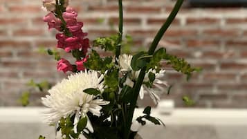 Un ramo de flores en un jarrón con un muro de ladrillo y un cuadro al fondo.
