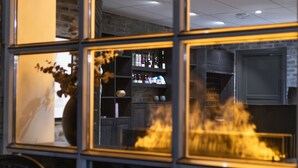 A modern interior with a fireplace, shelves with bottles, and a brick wall. - Aksjemøllen - by Classic Norway Hotels (Lillehammer)