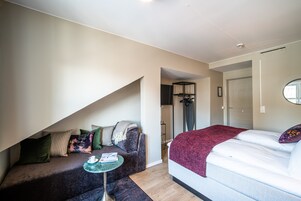 Un dormitorio con una cama, un sofá, una mesita y una puerta que da al baño.