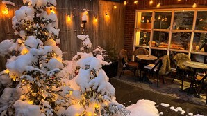 A snow-covered outdoor seating area with a wooden wall and string lights. - Aksjemøllen - by Classic Norway Hotels (Lillehammer)
