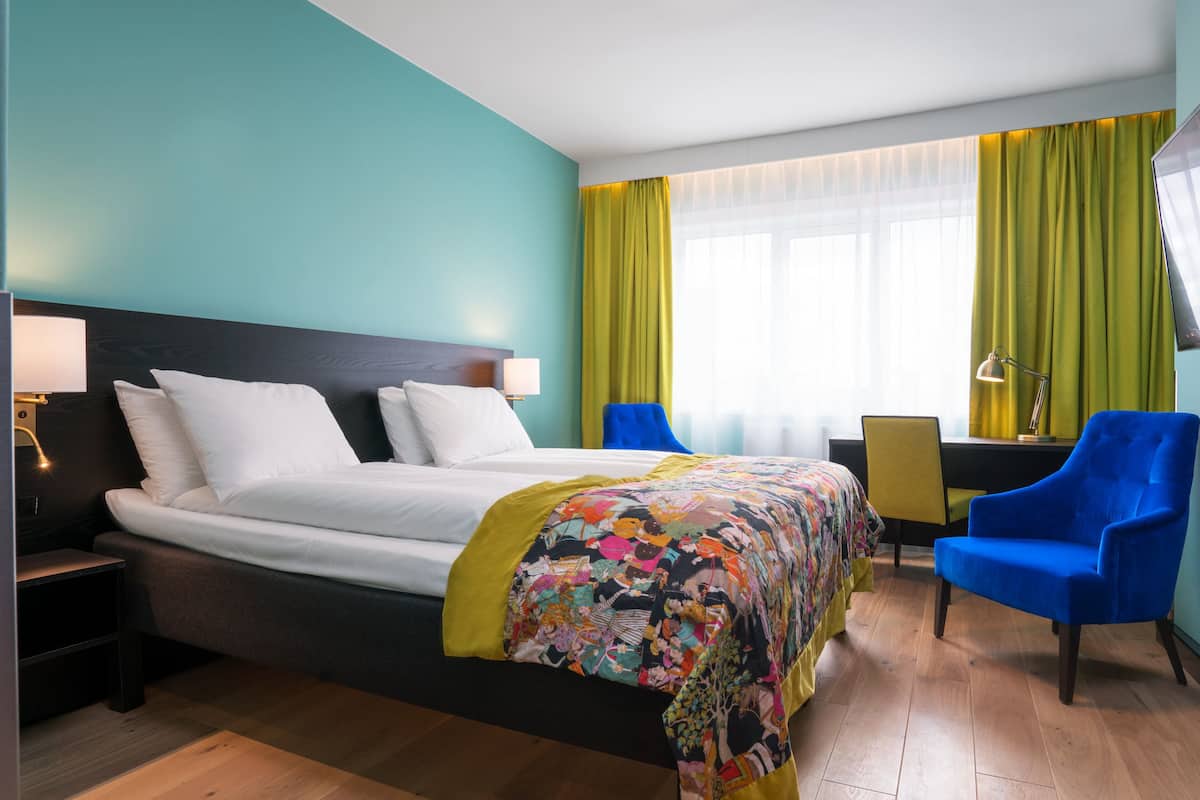 A hotel room with a bed, a desk, a chair, and a TV.
