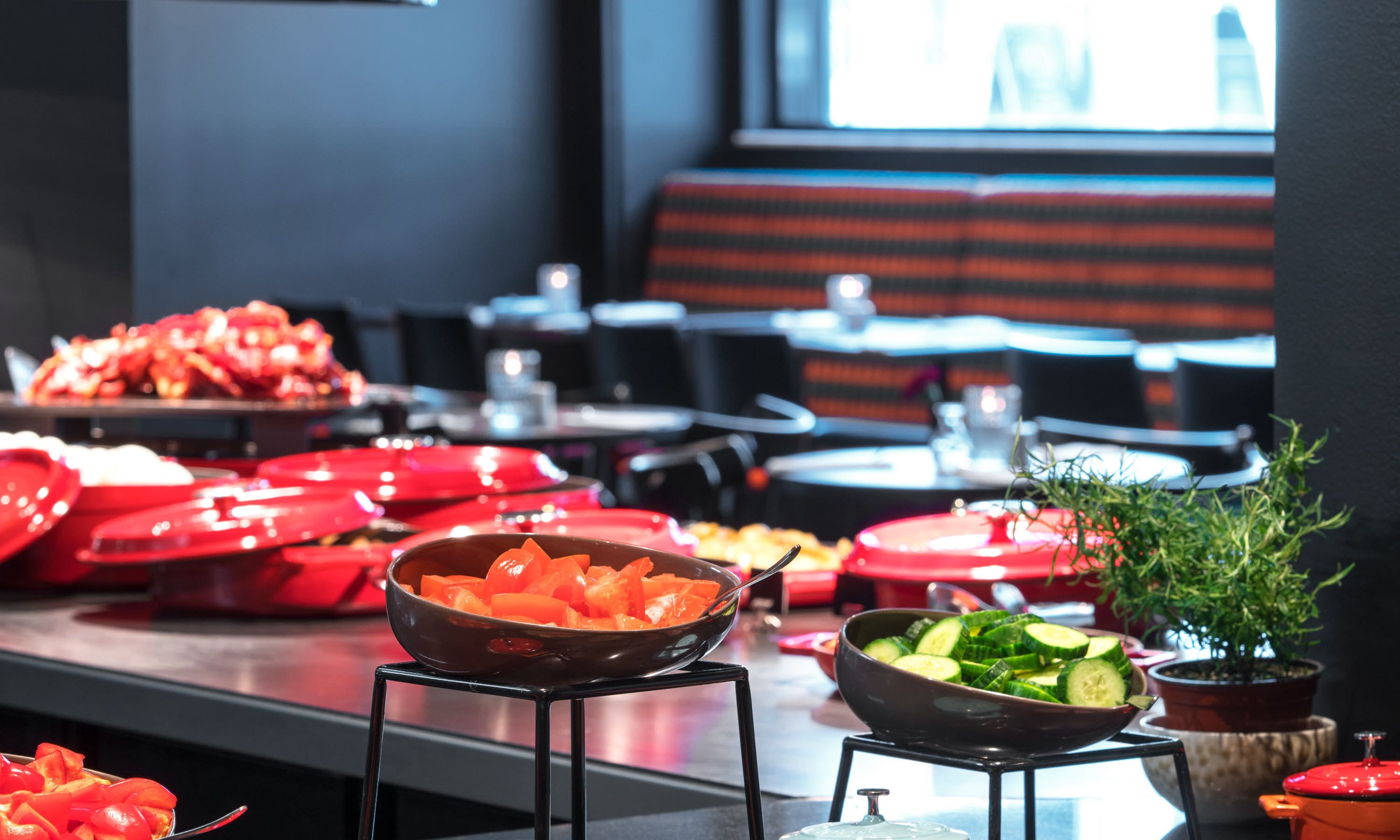 A buffet setup with various food items and a seating area in the background.