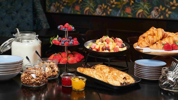 A breakfast buffet with various fruits, pastries, and dairy products.