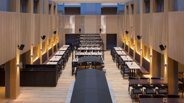 A modern dining area with long tables and chairs, wooden paneling, and ambient lighting. - Scandic Victoria (Oslo)