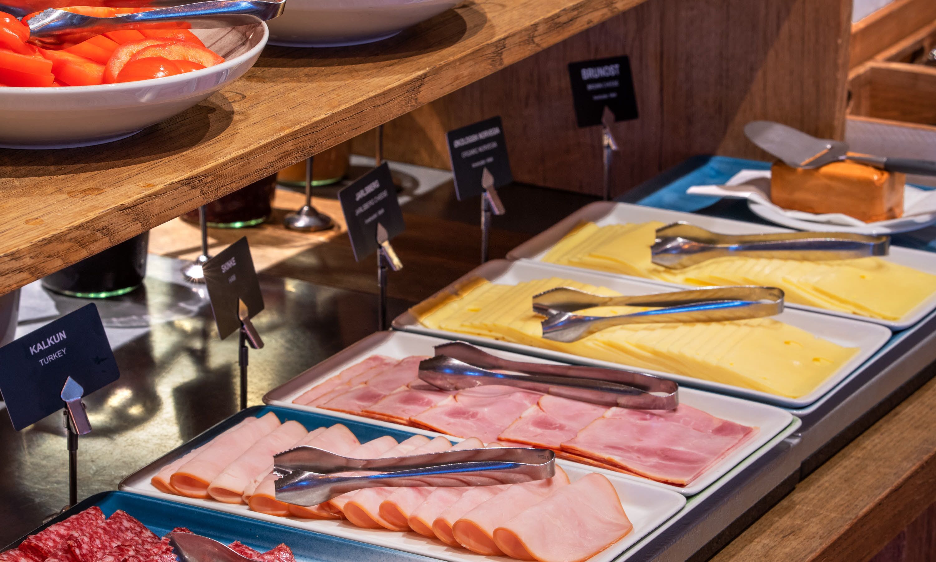 Ein Buffet mit verschiedenen Speisen, darunter Aufschnitt, Käse und eine Schüssel mit geschnittenen Karotten.