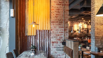 Ein rustikales Interieur mit freiliegenden Backsteinwänden, Holzbalken und Möbeln aus Metall und Holz.