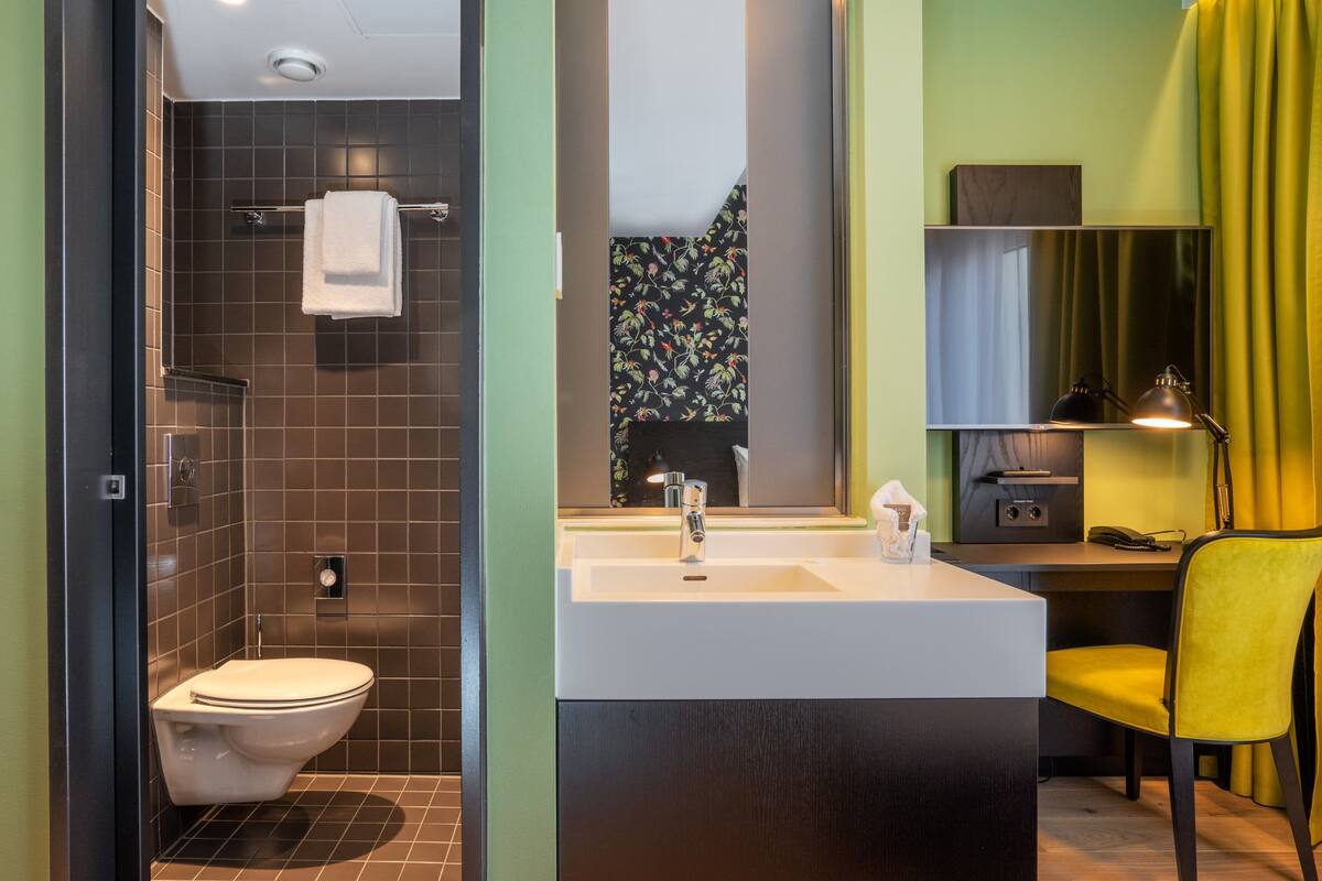 A modern bathroom with a shower, toilet, sink, and a mirror.