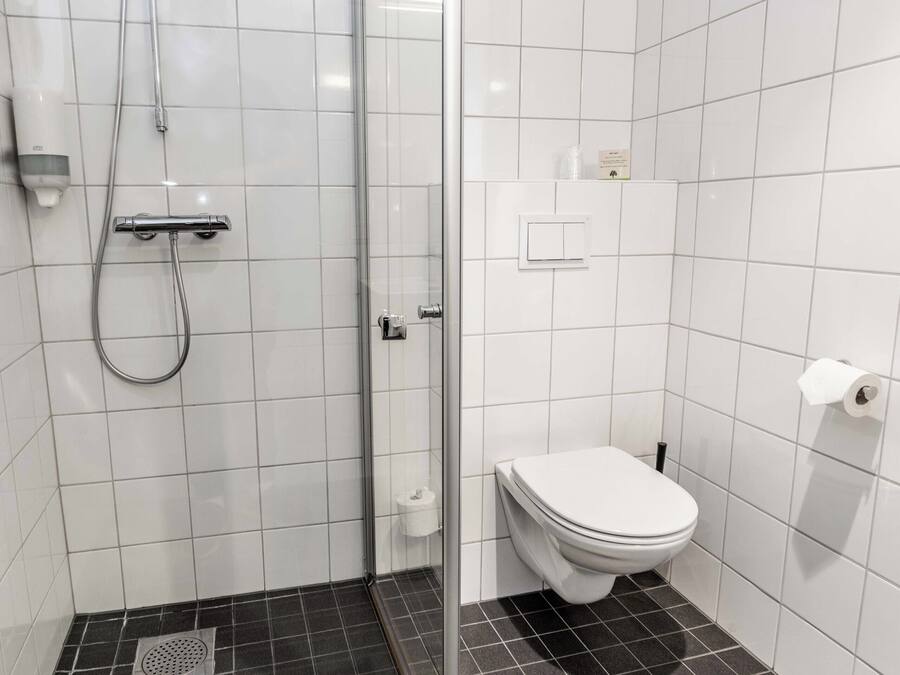 A bathroom with a shower, toilet, and tiled walls.