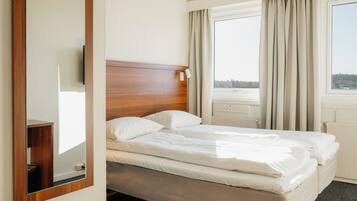 A hotel room with a large bed, a wooden headboard, a flat-screen TV, and a large mirror.