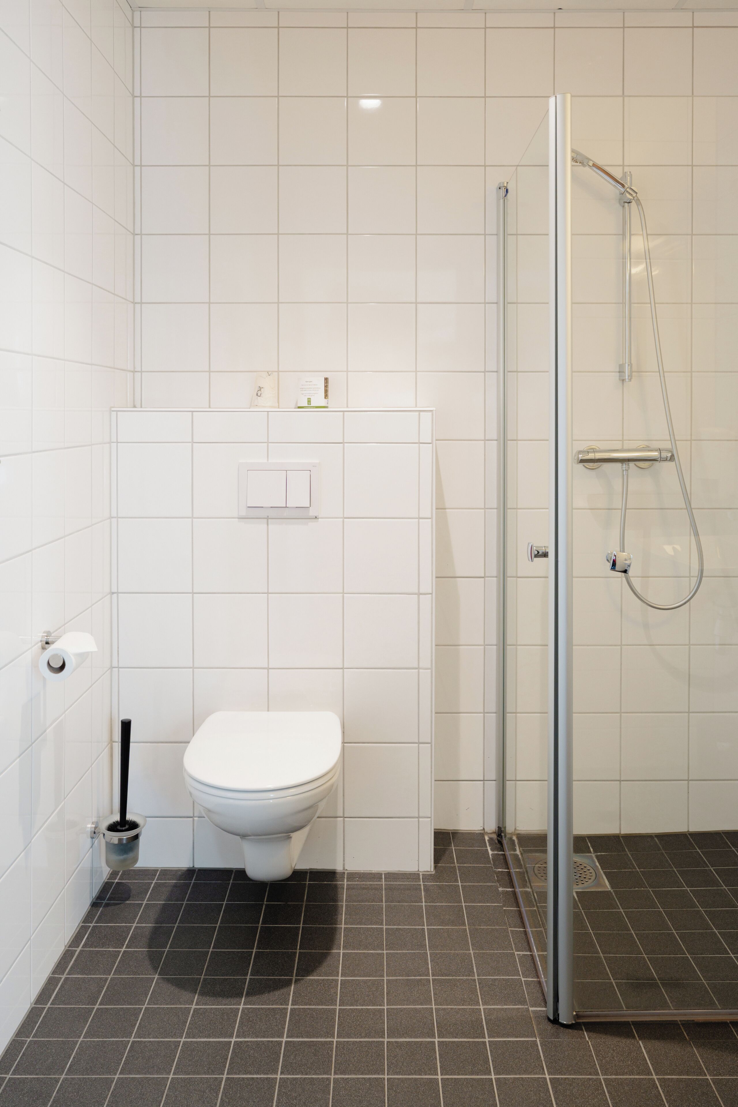 A modern bathroom with a toilet, a shower, and a tiled floor.
