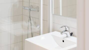 A modern bathroom with a glass-enclosed shower, a white sink, and a mirror above the sink.