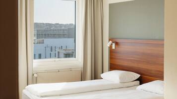 Habitación de hotel con dos camas, vista a una masa de agua y una ventana con cortinas.
