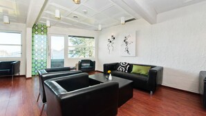 Una sala de estar moderna con un sofá de cuero negro, una mesa de centro y un sofá cama de cuero negro. Hay dos sillas negras y una pared de acento verde.