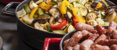 A buffet with various dishes including roasted potatoes, grilled vegetables, and sausages.