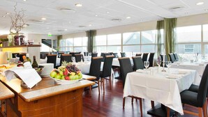 Un restaurante con varias mesas, un frutero y una botella de vino en la barra.