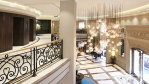 A grand hotel lobby with a marble floor, a curved staircase, and a decorative light fixture. - Four Points by Sheraton Lahore (Lahore)
