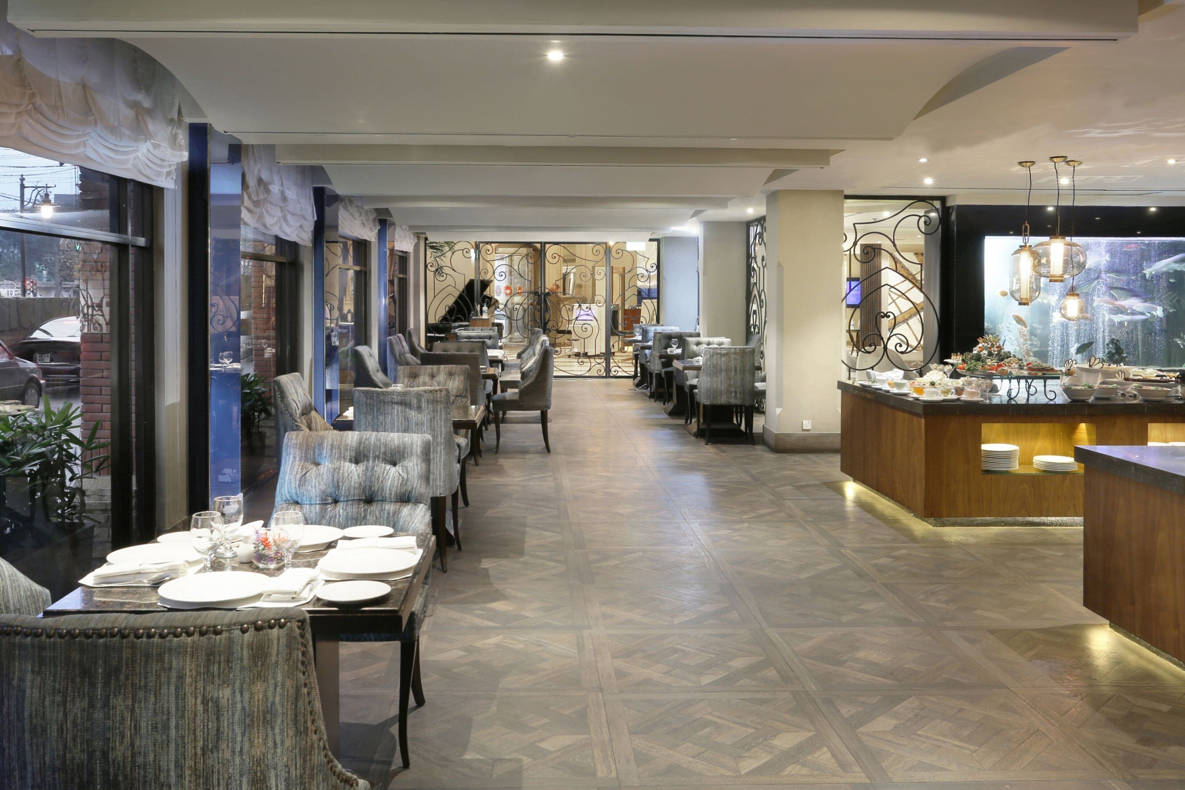A restaurant with a long dining area, a bar, and a view of the street.