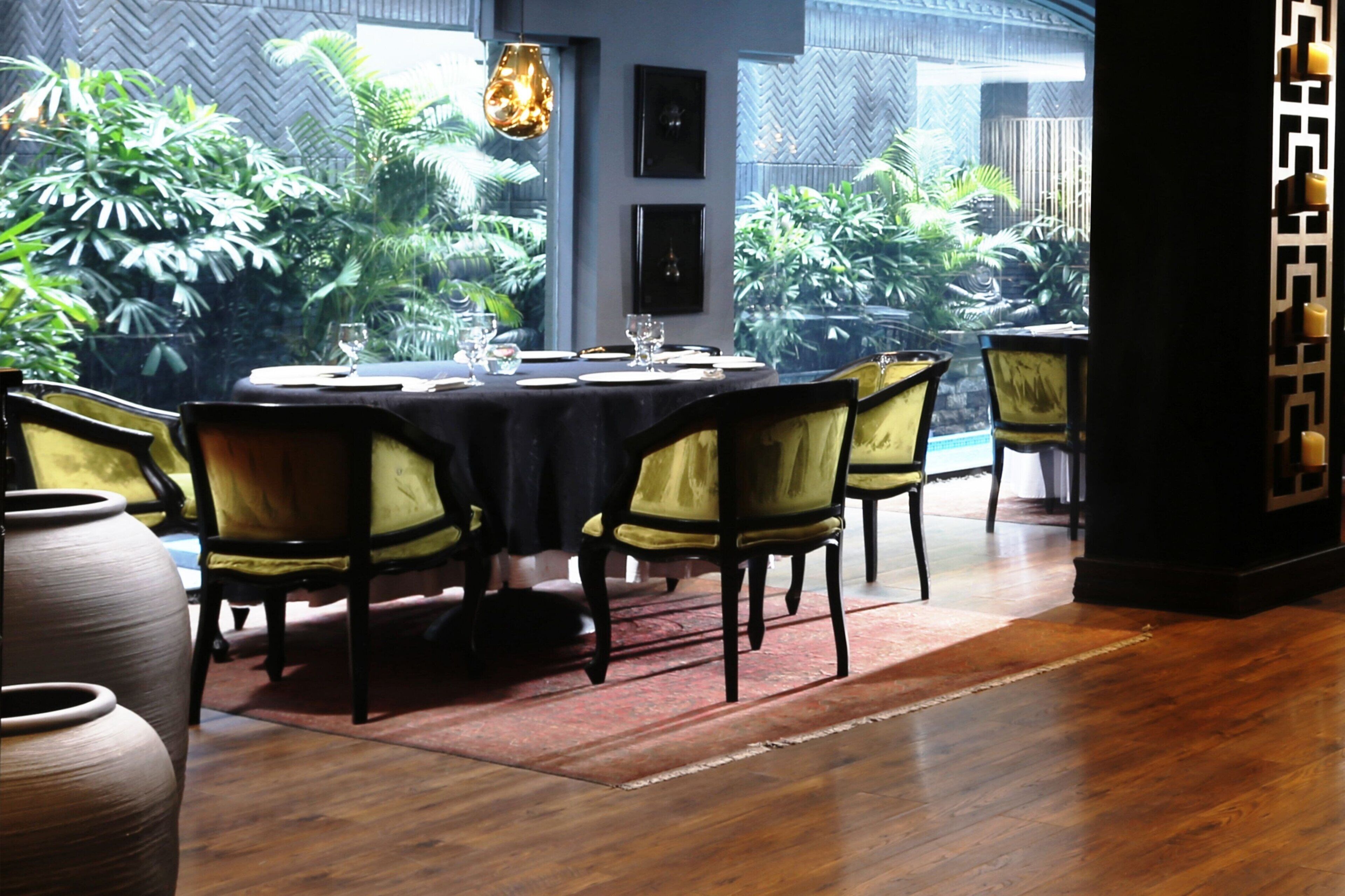Un comedor con una mesa redonda, sillas y vistas a la vegetación exuberante.