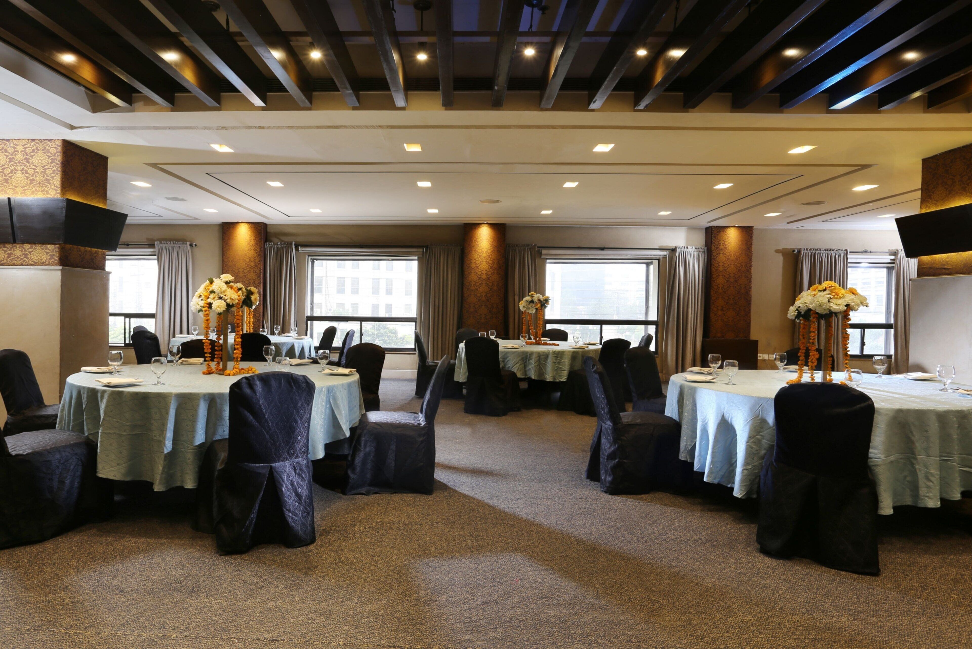 A conference room with round tables, black chairs, and floral centerpieces.