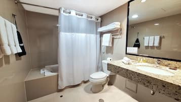 Un baño moderno con cortina de ducha, inodoro, lavamanos con espejo y varias toallas colgadas en la pared.