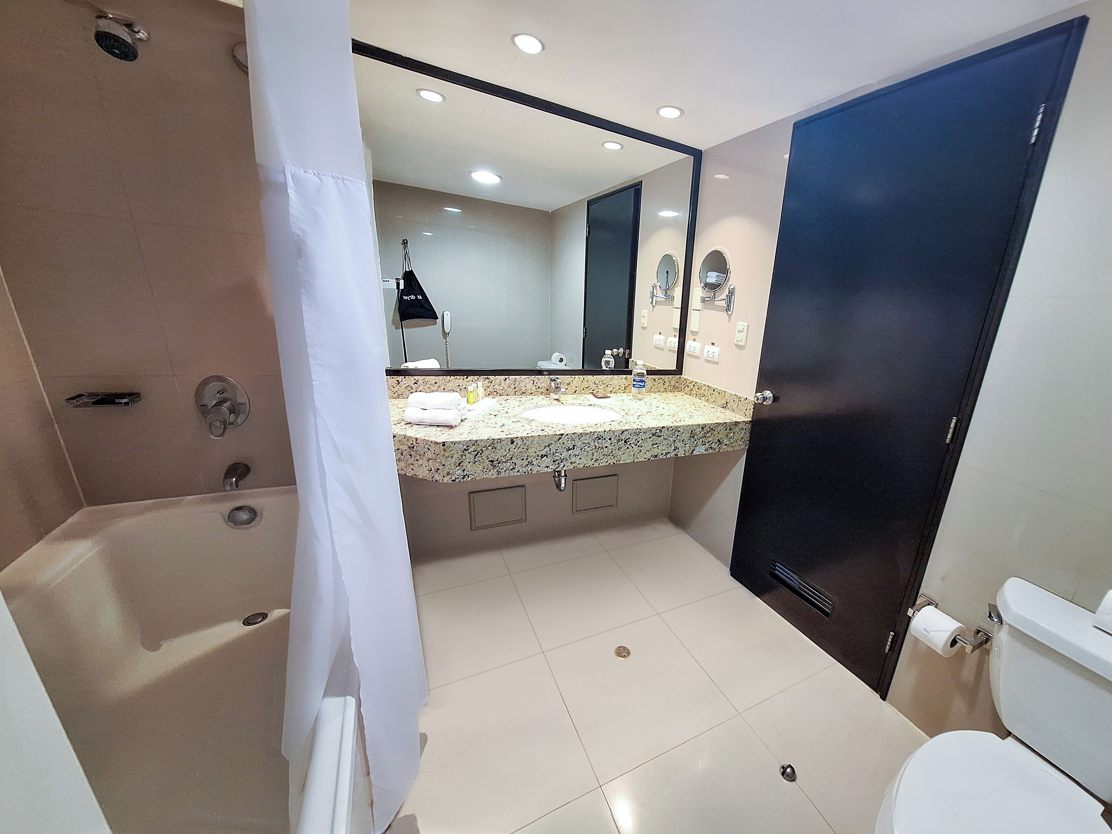 A modern bathroom with a large mirror, a sink, and a toilet.