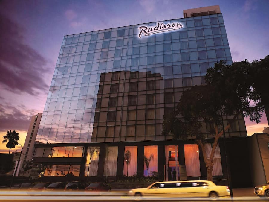 Un hotel Radisson con fachada moderna de vidrio, ventanas amplias y señalización llamativa.