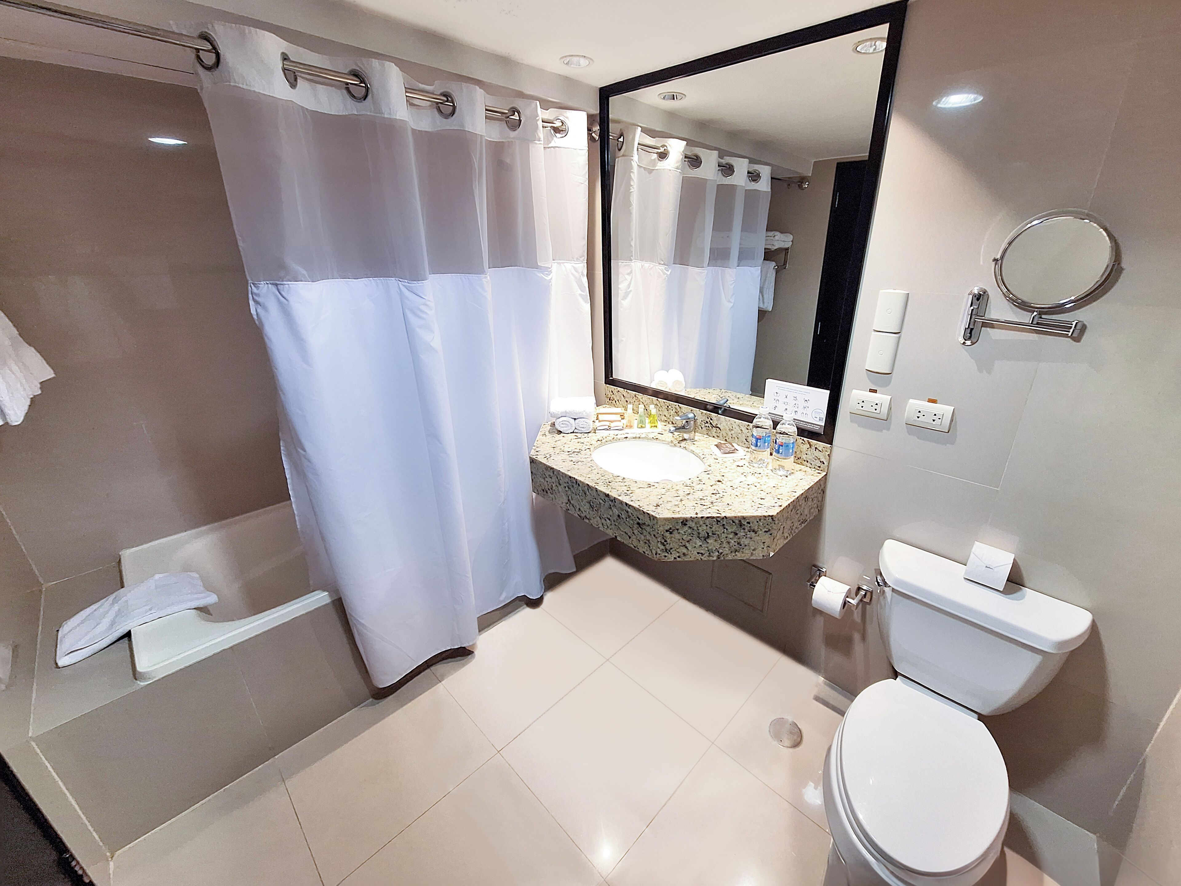 Un baño con ducha, lavamanos, inodoro y espejo.