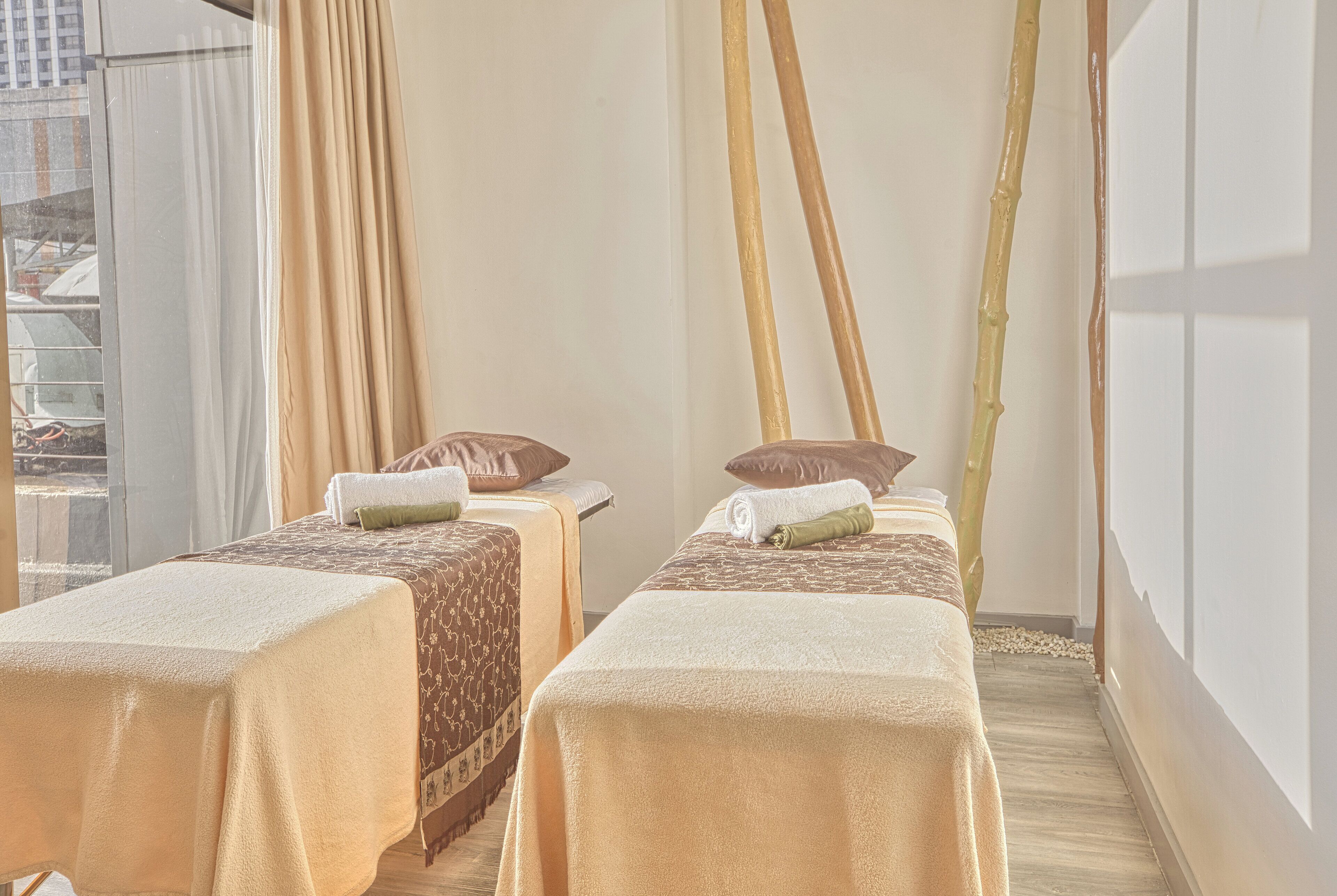 A spa room with two massage tables, each with a towel and a pillow.
