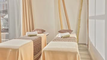 A spa room with two massage tables, each with a towel and a pillow.