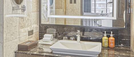 Une salle de bain moderne avec un grand miroir, des murs en marbre, un lavabo et un porte-serviettes.