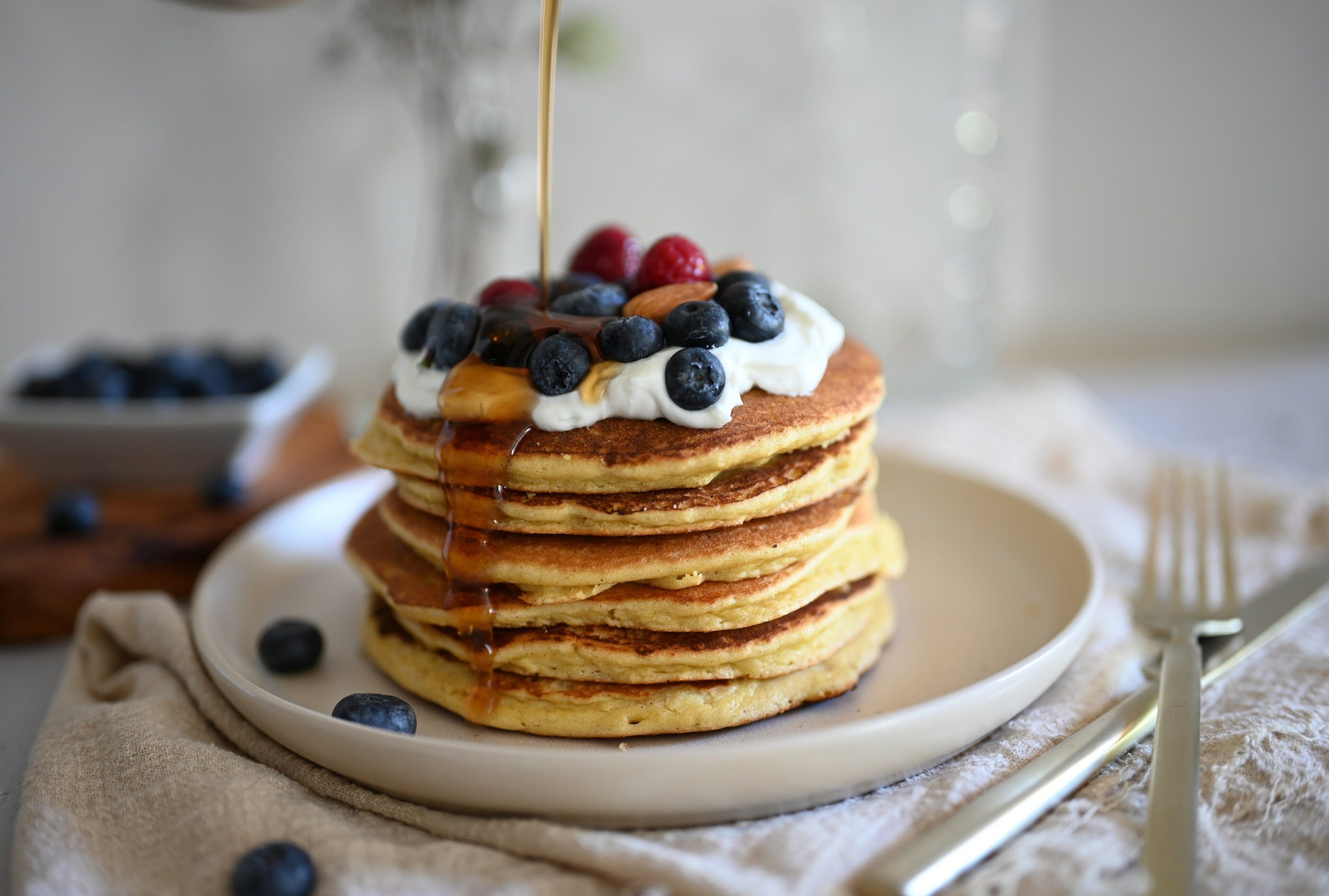 A stack of pancakes with blueberries and syrup on a plate.
