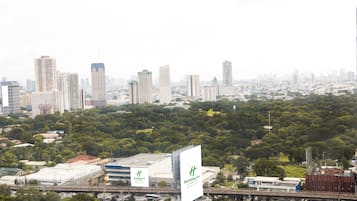 A cityscape with a Holiday Inn sign, high-rise buildings, and a dense green area in the foreground.