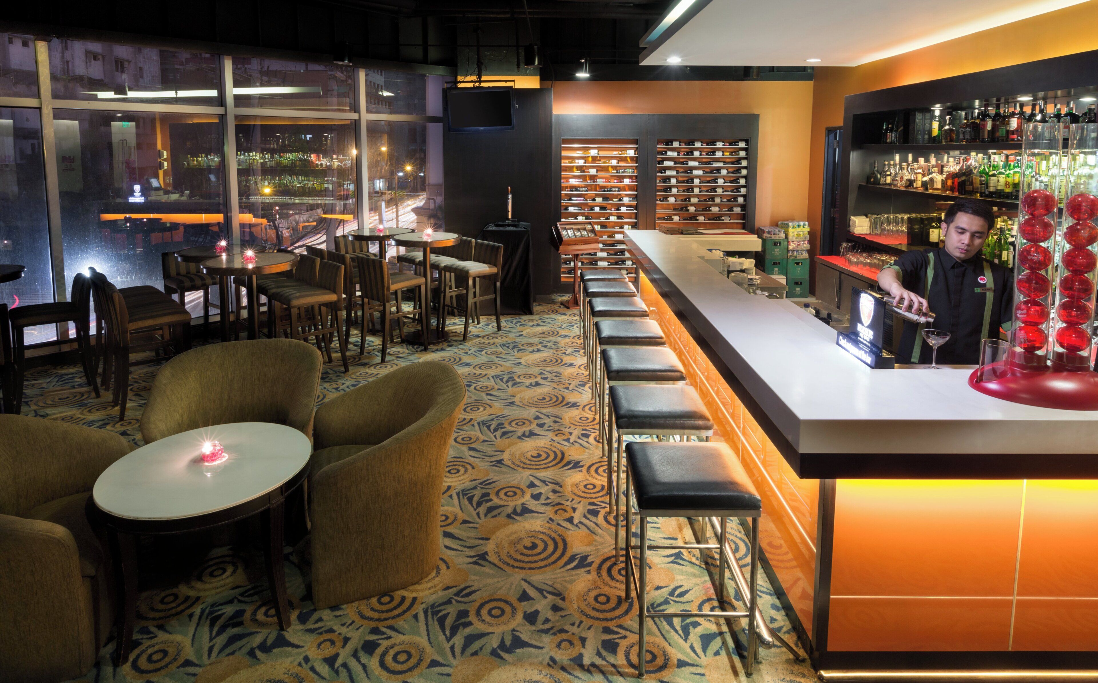 A bar area with seating, a bar counter, and shelves with bottles.