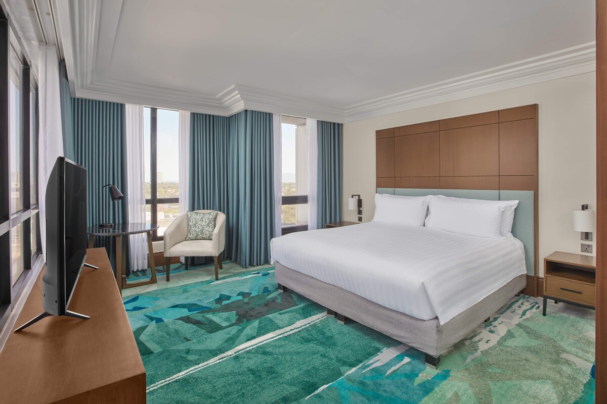 Une chambre d’hôtel avec un grand lit, une télévision, un bureau et une chaise.