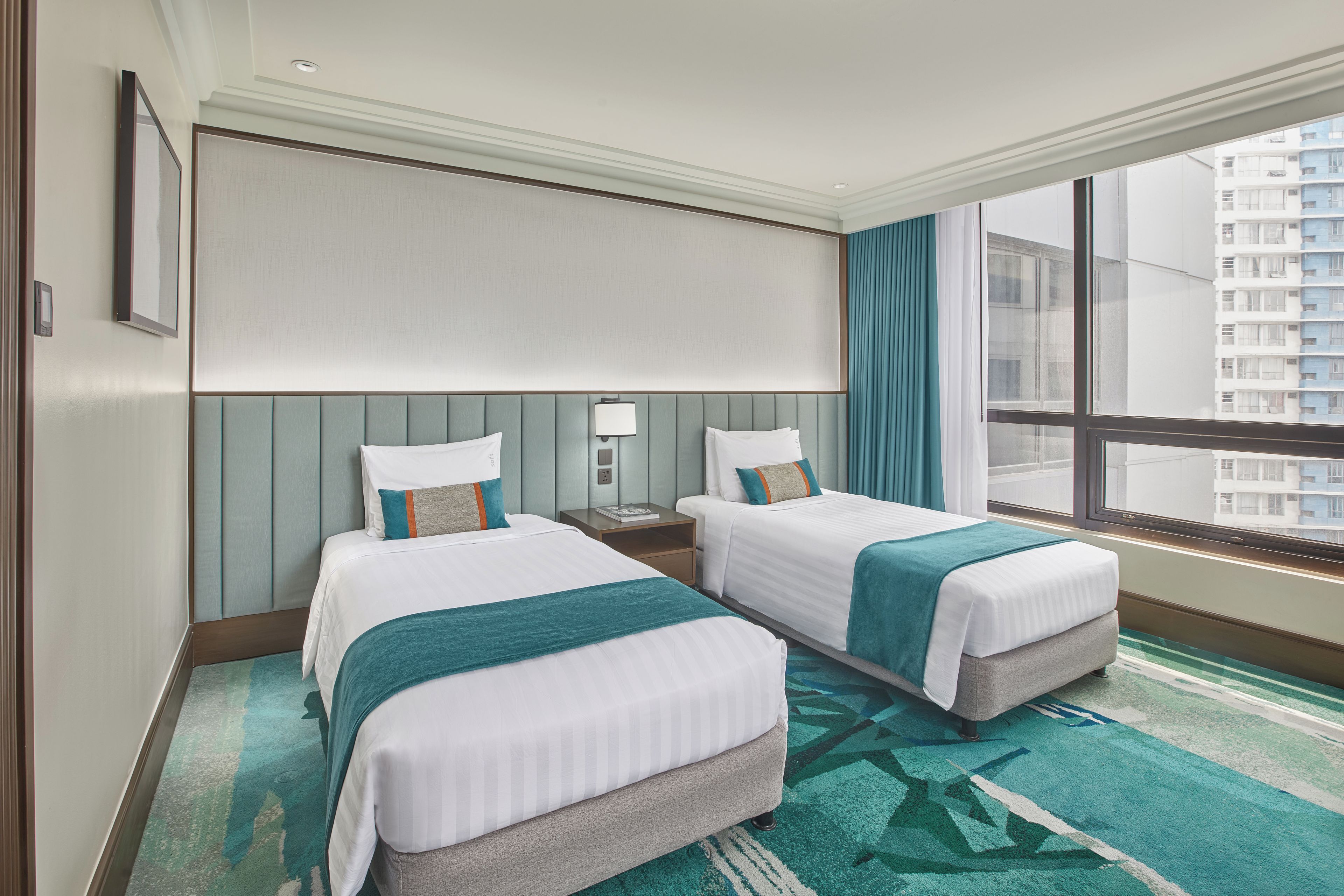 A hotel room with two beds, a large window, and a view of a building outside.