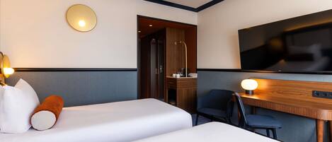 Een hotelkamer met twee bedden, een bureau met stoel, een televisie en een bureaulamp.
