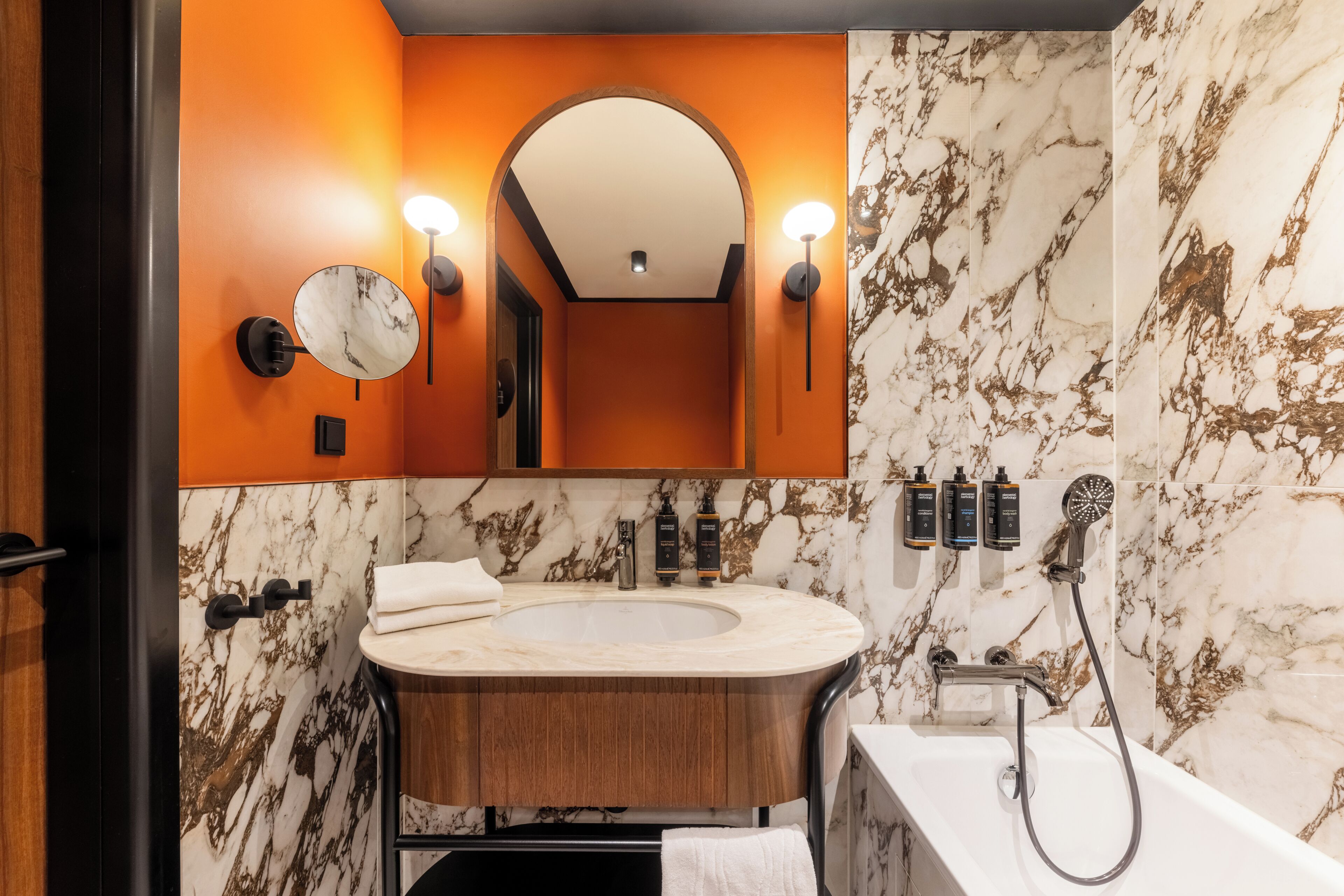 Une salle de bain avec un lavabo en marbre, un meuble-lavabo en bois, un grand miroir et une douche.